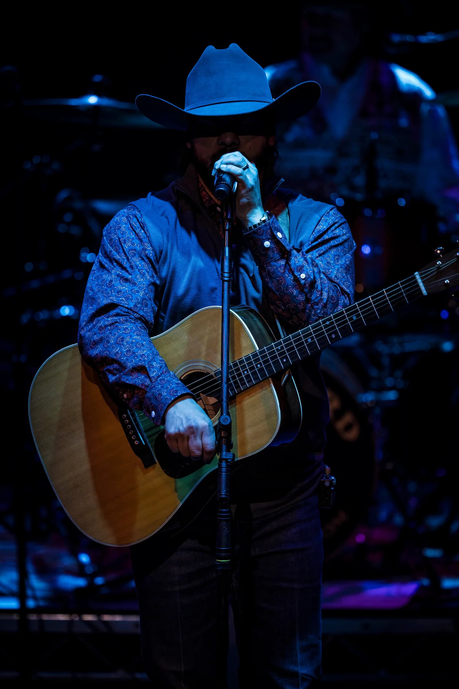 Buck Ford singing into a microphone with his acoustic guitar