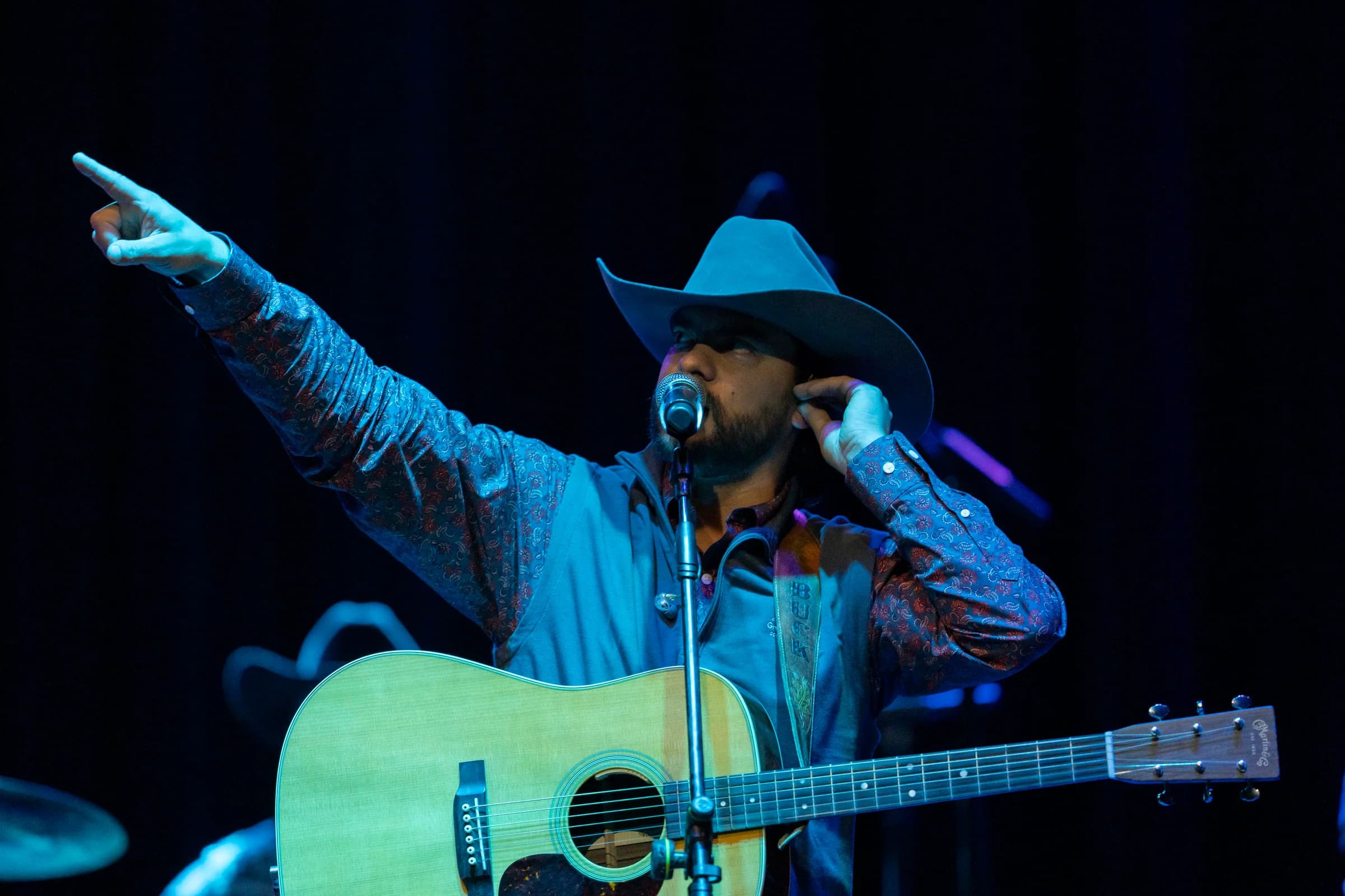 Buck Ford pointing toward the crowd with his guitar across his chest