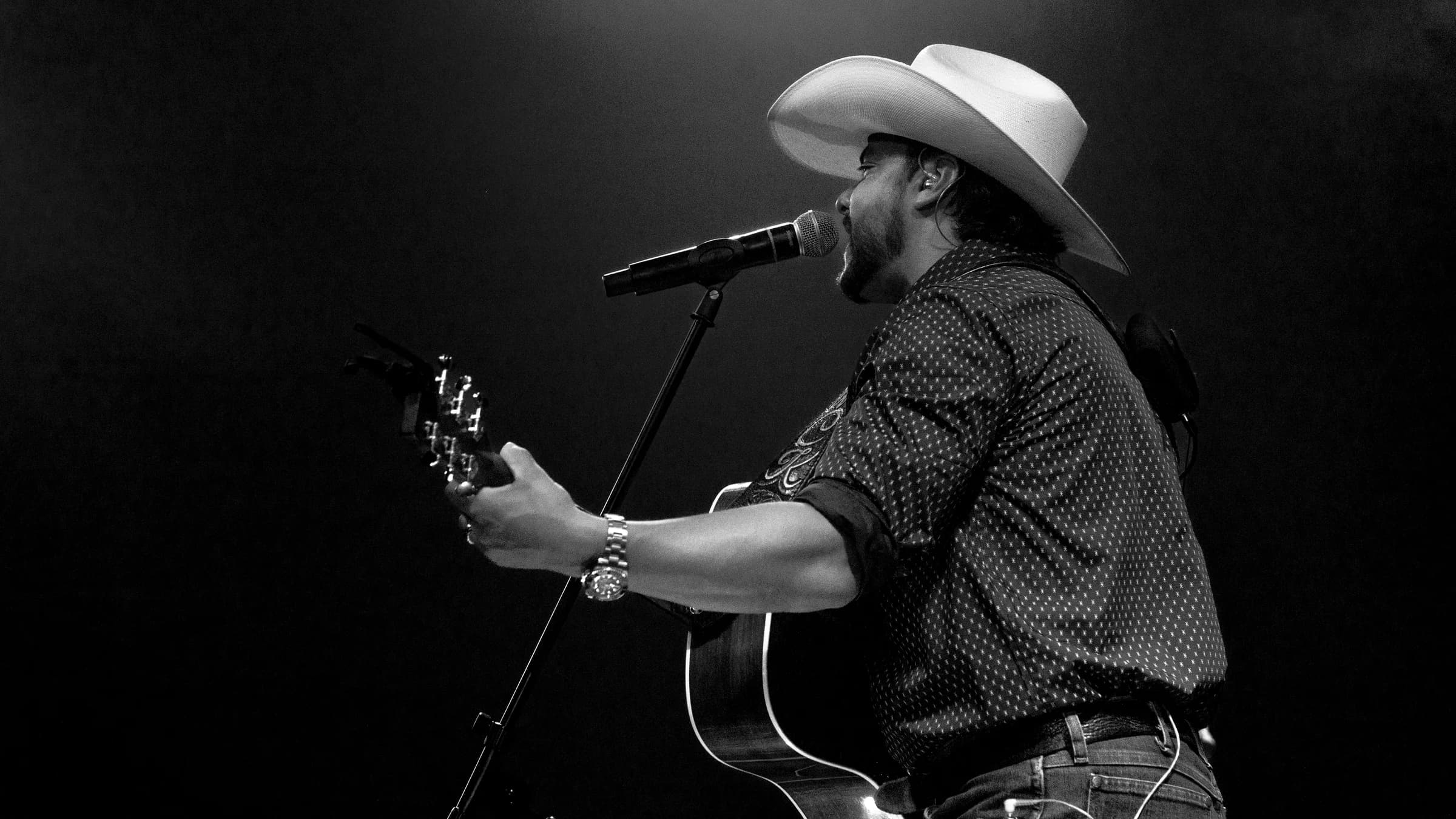 Buck Ford singing into the microphone with his acoustic guitar