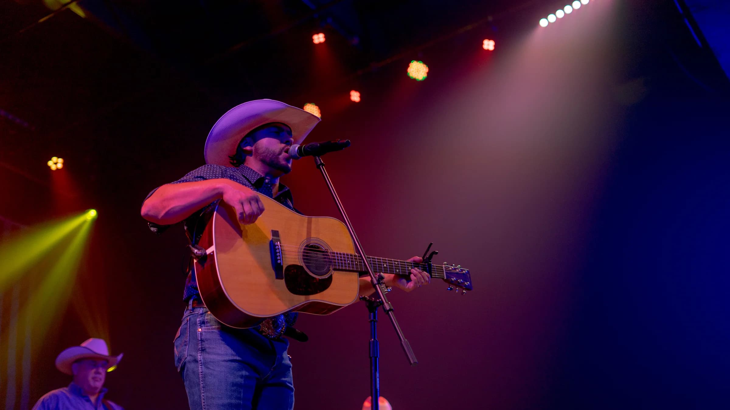 Buck Ford playing guitar beneath red and purple stage lights