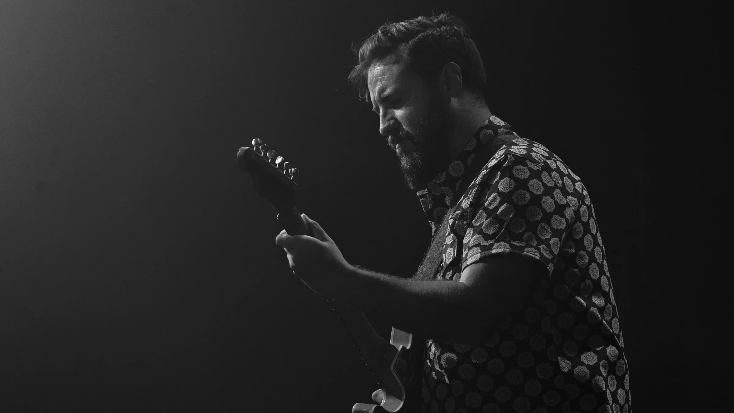 Electric guitarist performing in a black-and-white stage portrait