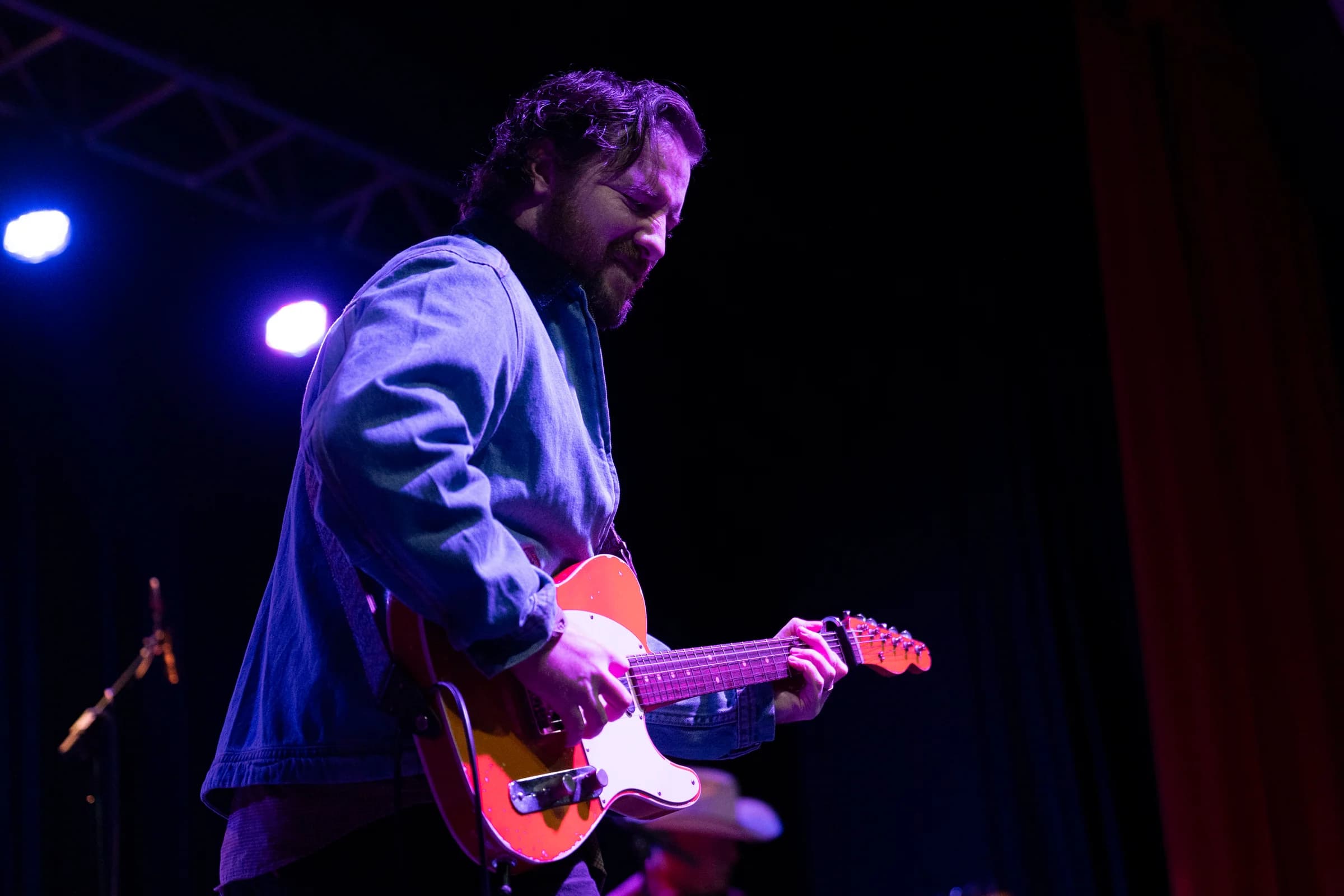 Electric guitarist playing under purple and red stage lights