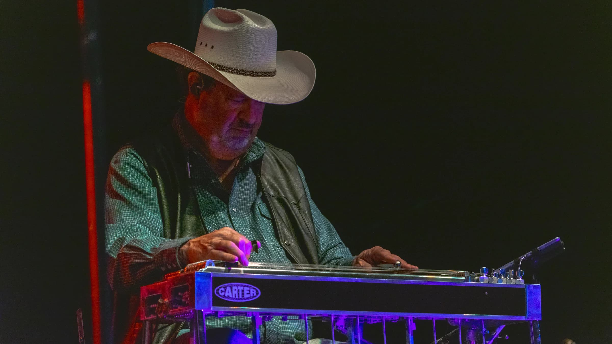 Steel guitarist in a cowboy hat seated at his instrument