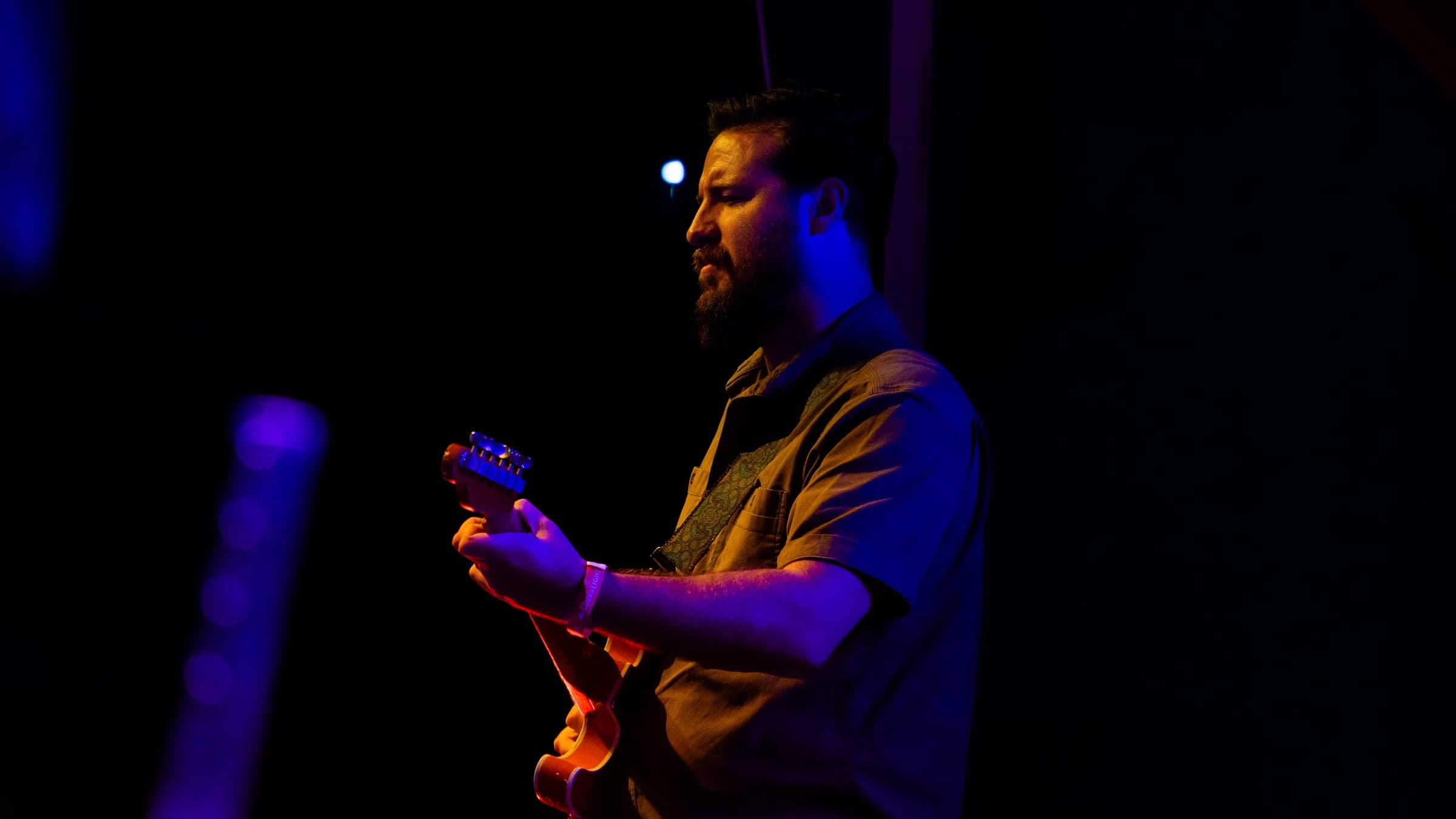 Electric guitarist playing in the shadows of the stage