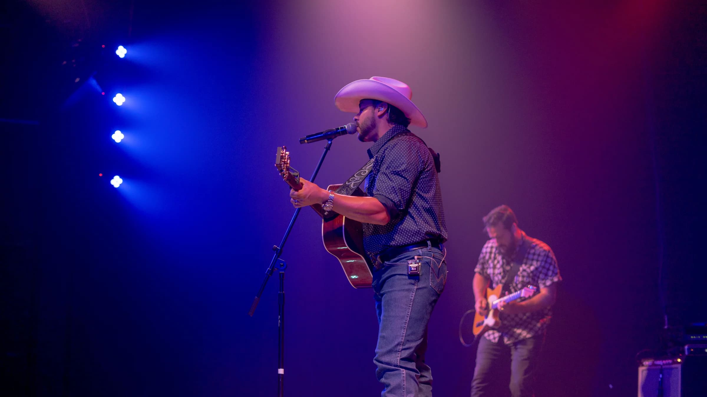 Buck Ford and the band performing beneath blue and purple lights